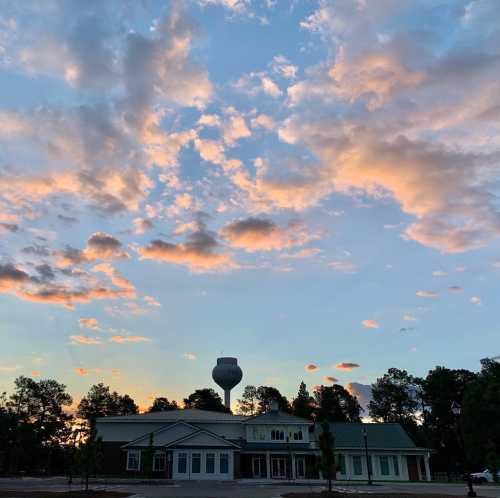 A building with a water tower against a colorful sunset sky filled with clouds.