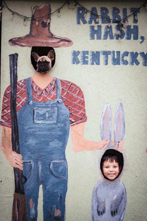 A painted mural of a farmer and a rabbit, with a dog and a child peeking through cut-out holes.