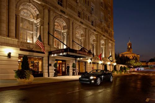Elegant hotel entrance at night, featuring a luxury car parked outside and illuminated architecture.