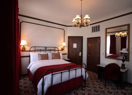 Cozy hotel room featuring a queen bed, elegant decor, a mirror, and warm lighting.