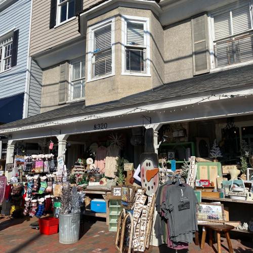 A charming storefront with various items for sale, including clothing and decorations, under a sunny sky.