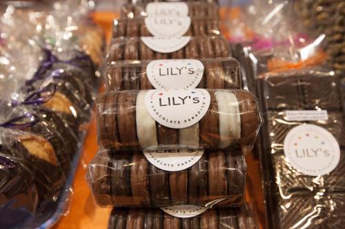 Stacks of chocolate-covered cookies labeled "Lily's Chocolate Paradoxes" on a colorful display.