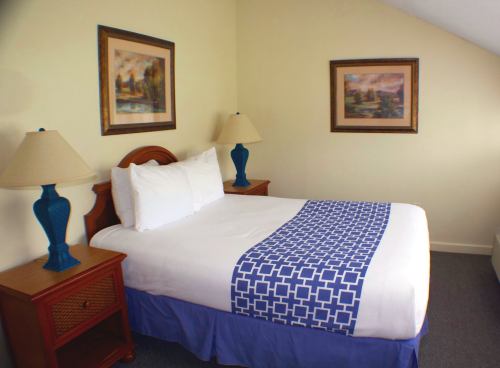 Cozy bedroom with a double bed, blue and white decor, two lamps, and framed artwork on the walls.