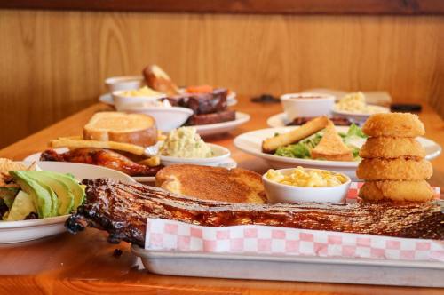 A table filled with various barbecue dishes, including ribs, sides, and desserts, arranged on plates.