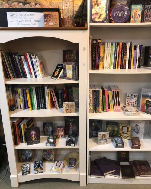 A bookshelf filled with various books and tarot decks, labeled "This is a lamp" on the top shelf.
