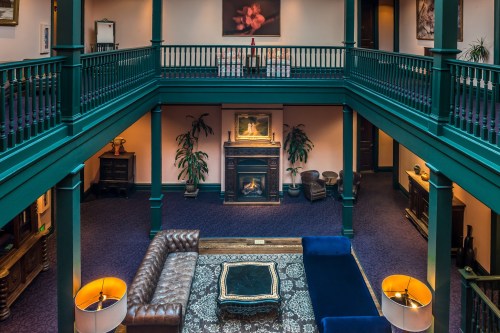 A spacious, elegant interior with green railings, a cozy fireplace, and stylish furniture on a plush carpet.