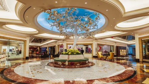 Elegant hotel lobby featuring a large decorative tree, marble flooring, and stylish seating areas.