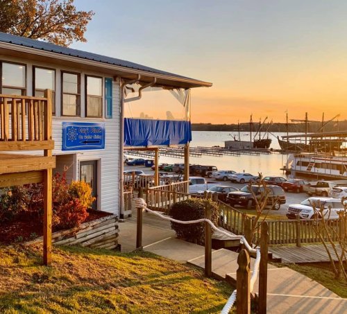 A waterfront restaurant at sunset, with boats docked and a scenic view of the water and trees.