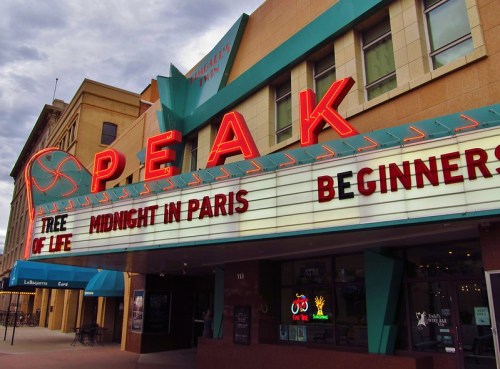 A theater marquee displays the titles "Tree of Life," "Midnight in Paris," and "Beginners" under the name "PEAK."