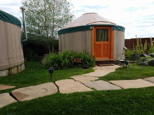 A pathway leads to a cozy yurt with a wooden door, surrounded by greenery and stone lanterns.