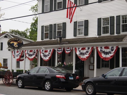 Exterior of the Griswold Inn, decorated with red, white, and blue bunting, featuring parked cars and an American flag.