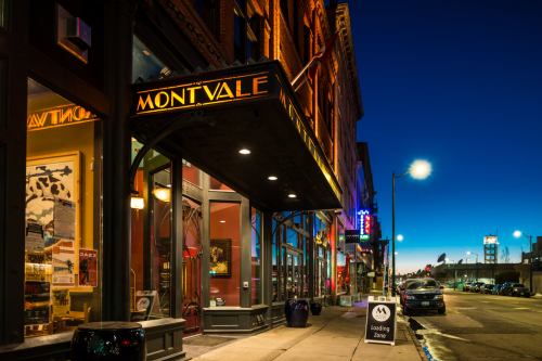 Exterior of Montvale building at dusk, featuring warm lights and a street view with parked cars and a sign.
