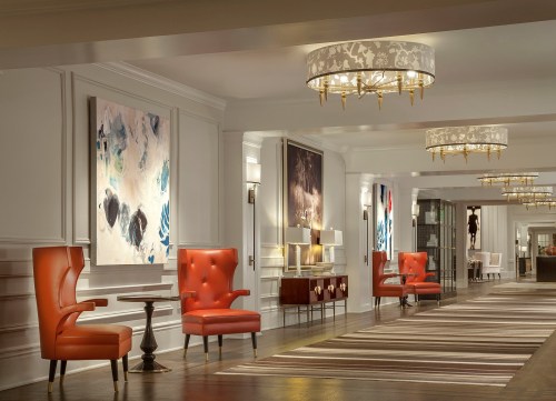 Elegant hotel lobby featuring red chairs, modern artwork, and stylish lighting fixtures.