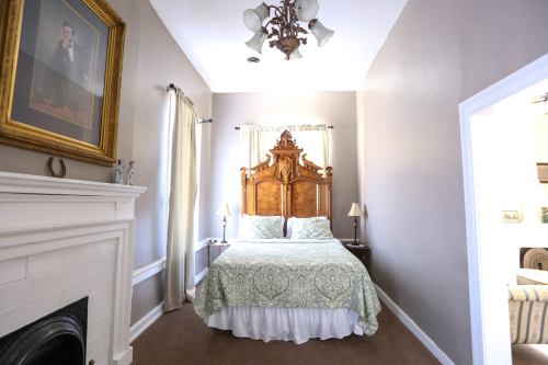 Cozy bedroom with a wooden bed, decorative headboard, and soft green bedding, featuring a fireplace and framed artwork.