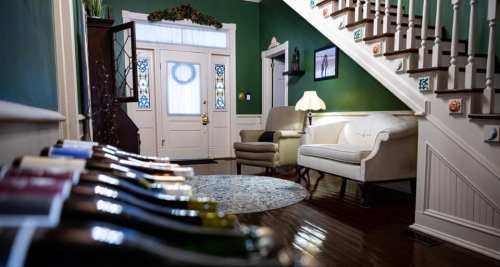 A cozy entryway with a staircase, a sofa, and a decorative rug, featuring a wine rack in the foreground.