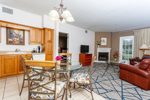 Cozy living area with a dining table, kitchen, fireplace, and comfortable seating in a well-lit space.