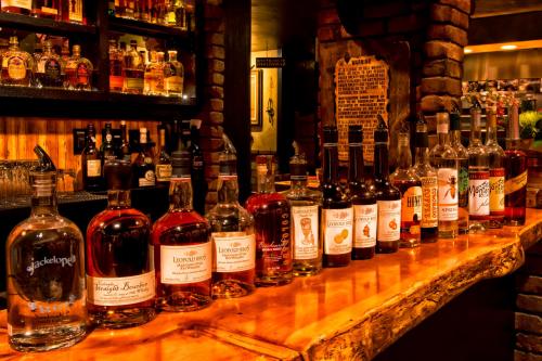 A wooden bar displaying a variety of liquor bottles, with shelves of spirits in the background. Warm, inviting atmosphere.