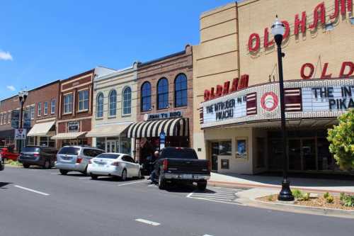 A charming street scene featuring historic buildings, parked cars, and a theater marquee in a sunny town.