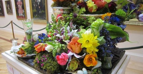 A vibrant floral arrangement featuring various colorful flowers displayed in an art gallery setting.
