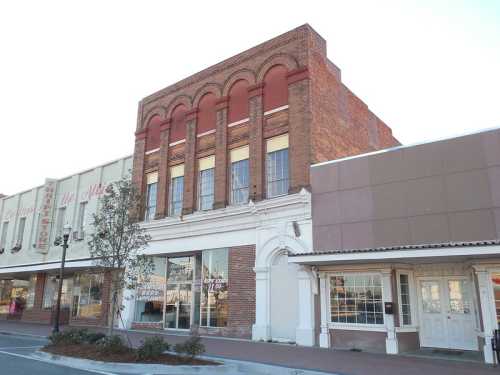 Historic brick building with arched windows, featuring a mix of architectural styles and a modern storefront below.