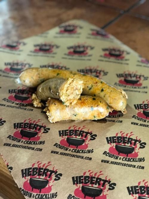 A stack of boudin sausages on branded paper from Hebert's Boudin & Cracklins.