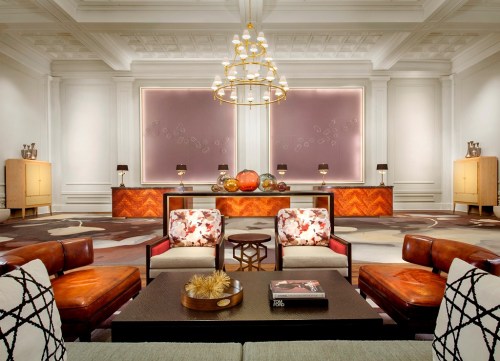 Elegant hotel lobby featuring stylish seating, a chandelier, and a decorative reception desk. Warm, inviting atmosphere.
