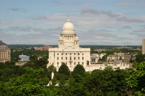 A view of a large white dome building surrounded by greenery and cityscape under a blue sky with clouds.