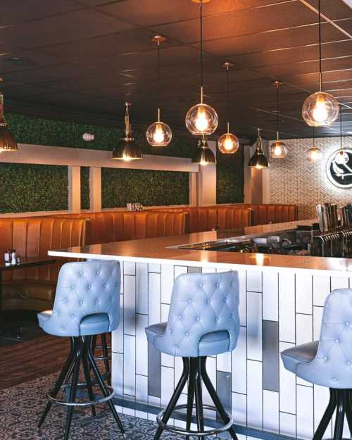 Modern bar interior featuring stylish stools, pendant lights, and a green wall accent.