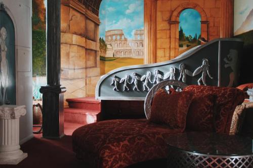 A cozy room featuring a decorative chaise lounge, ornate wall murals, and a unique staircase design.