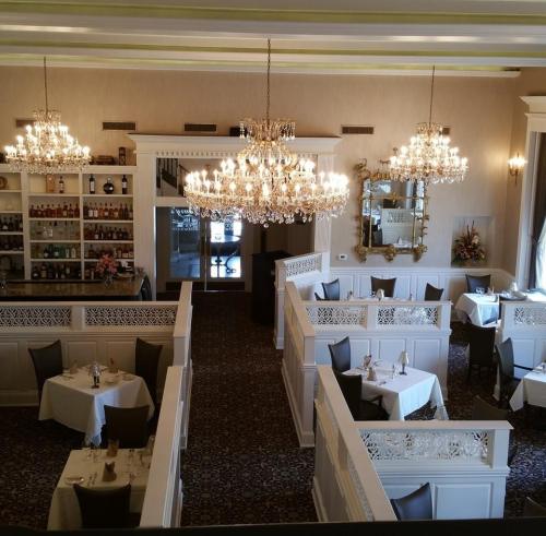 Elegant restaurant interior with white decor, chandeliers, and neatly arranged tables in cozy booths.