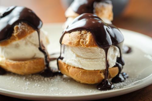 A close-up of ice cream sandwiches drizzled with chocolate sauce on a plate, dusted with powdered sugar.