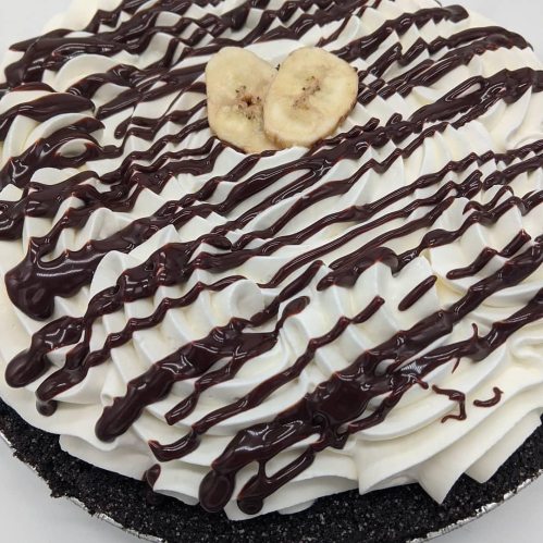 A chocolate cream pie topped with whipped cream, drizzled chocolate, and banana slices.