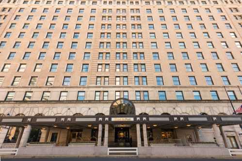 A large, historic hotel building with a symmetrical facade and multiple windows, featuring an entrance with a circular design.