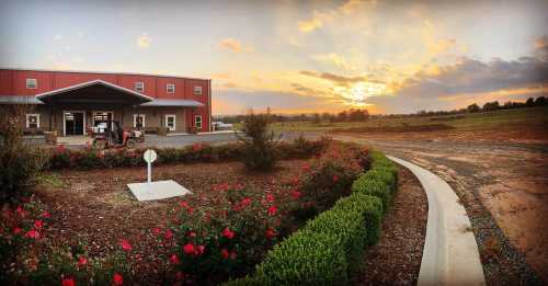 A sunset over a building surrounded by landscaped gardens and a gravel path, with flowers in bloom.