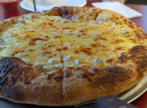 A freshly baked cheese pizza with a golden crust, served on a metal tray.