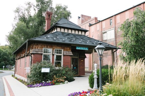 A charming brick building with a shingled roof, surrounded by flowers and greenery, labeled "Lititz."