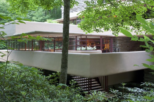 A modern architectural structure nestled among lush greenery, featuring large windows and a cantilevered design.