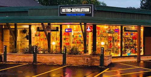 A vintage store named "Retro-Revolution" with colorful displays and bright lights, set in a charming building.