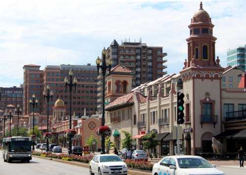 A busy street scene featuring a bus, cars, and buildings with decorative architecture and traffic lights.