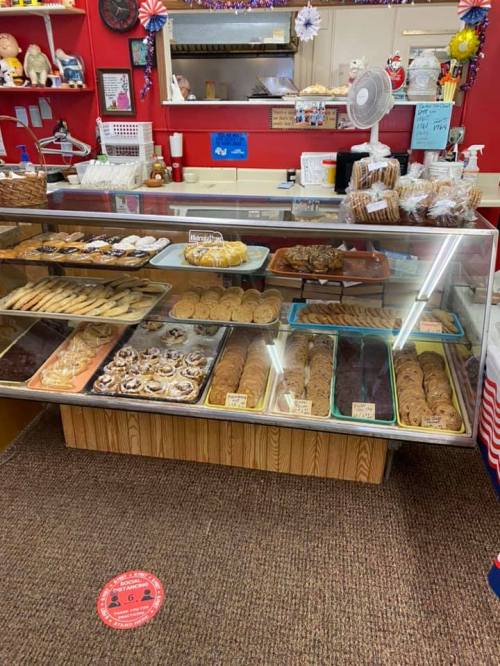 A display case filled with various baked goods, including cookies, pastries, and cakes, in a cozy bakery setting.