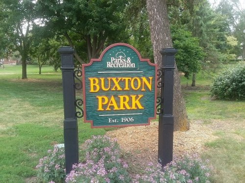 Sign for Buxton Park, established in 1906, surrounded by greenery and flowers.