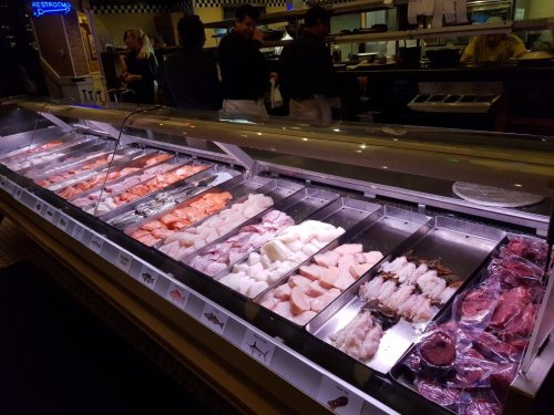 A seafood display case filled with various types of fresh fish and seafood in a restaurant setting.