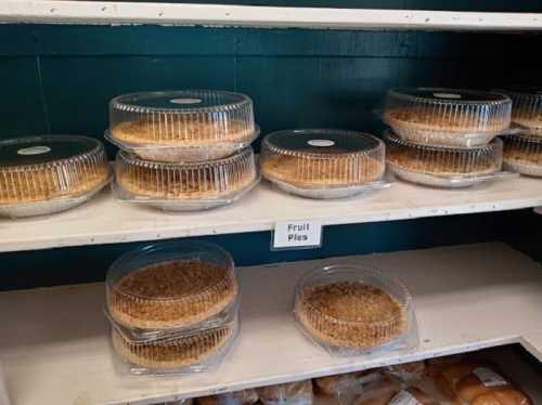 A display of fruit pies in clear containers on a shelf, labeled "Fruit Pies."