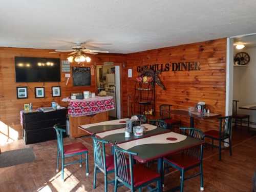 Cozy diner interior with wooden walls, tables, and a TV, featuring a welcoming atmosphere and a menu board.