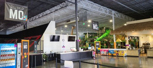Indoor play area featuring colorful slides, a reception desk, vending machines, and a vibrant atmosphere.