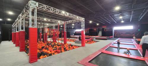 Indoor trampoline park featuring various trampolines, a foam pit, and climbing structures in a vibrant setting.