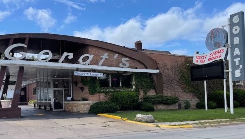 Exterior of Gorat's restaurant, featuring a modern sign and a classic brick building with greenery.