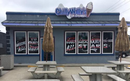Exterior of Chilly Willy's Ice Cream shop with picnic tables and colorful signage welcoming customers.