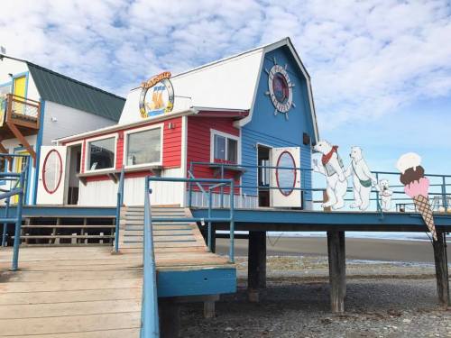 Colorful ice cream shop on a pier, featuring polar bear decorations and a wooden walkway leading to the entrance.
