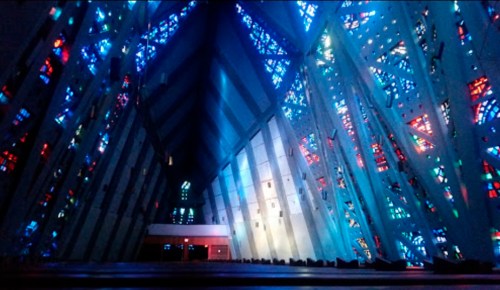 A vibrant interior of a modern church with colorful stained glass windows illuminating the space.